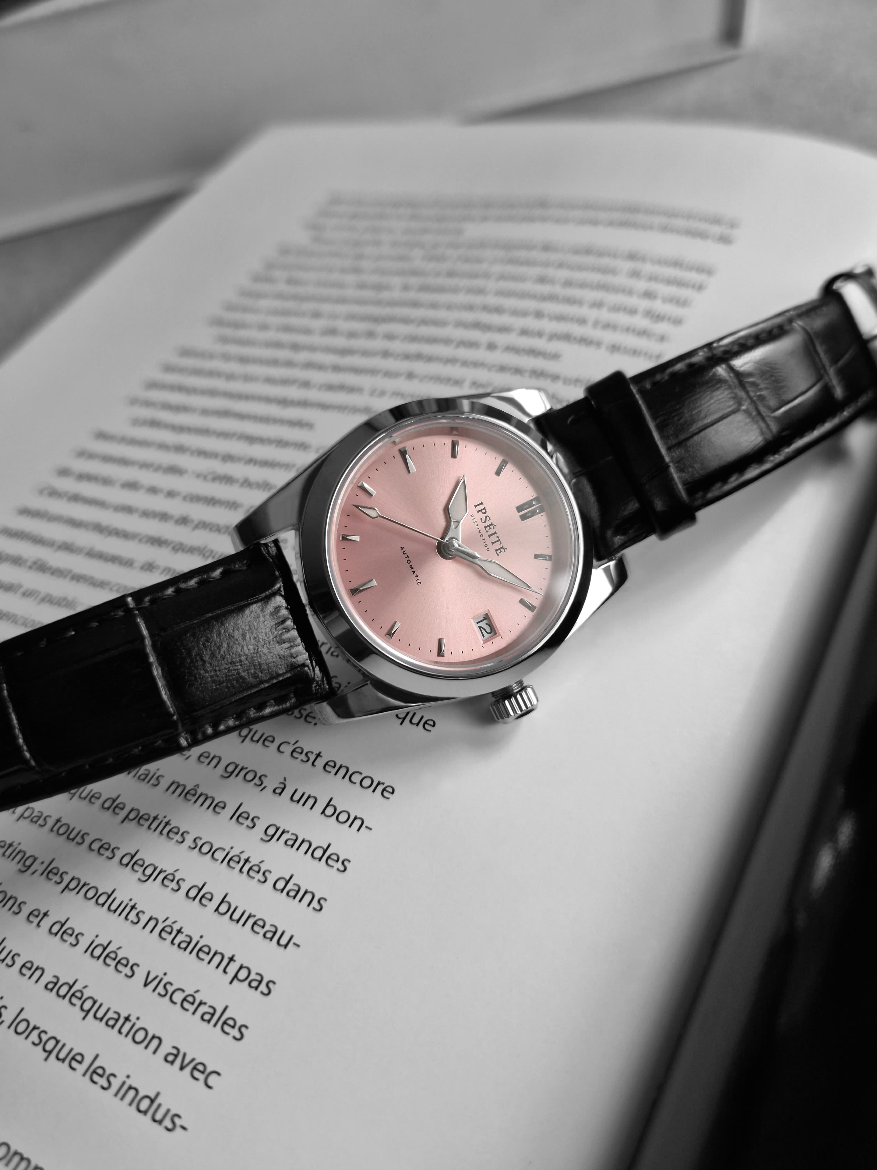 Distinction cadran rose posée sur un livre ouvert